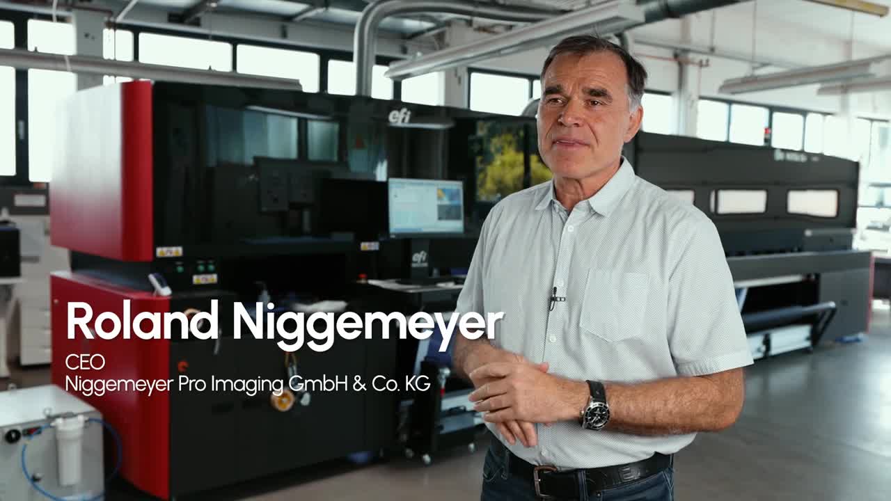 Roland Niggemeyer, CEO of Niggemeyer Pro Imaging, stands in front of the EFI VUTEk X5r roll-to-roll printer to discuss how the printer has helped the business with exceptional image quality, powerful automation, and an integrated print-to-finished-graphic workflow.
